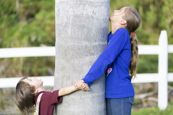 Glückliche Kinder umarmen einen Baum — Stockfoto
