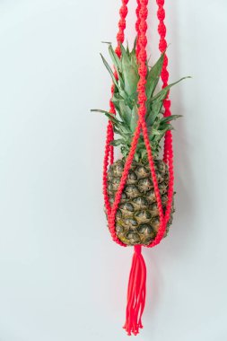 Kırmızı makrome duvar askısında taze ananas.