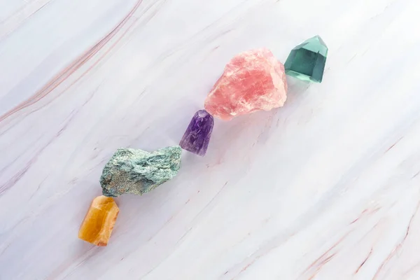 Kristallsteine auf einem Marmorhintergrund. Flache Lage aus verschiedenen Edelsteinen und Kristallen. — Stockfoto