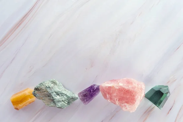 Crystal stones on a marble background. Flat lay of colorful gemstones and crystals with copy space — стоковое фото