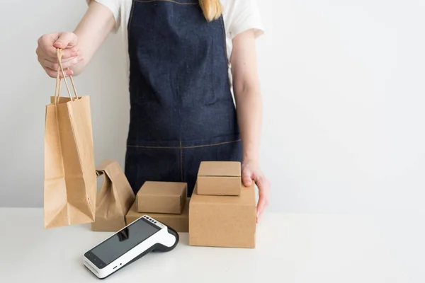 Frau in blauer Jeansschürze gibt einer Kundin die Papiertüte mit einer Bestellung — Stockfoto