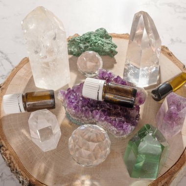 Essential oil glass bottles, beautiful crystals and gemstones on wooden log slice. Healing minerals and essential oil bottles for alternative medicine