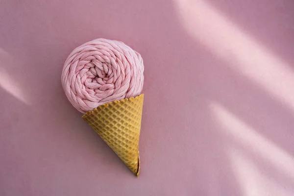 Vista superior do novelo de fios de macarrão rosa em cone de waffle de sorvete em um fundo rosa com raios de luz solar — Fotografia de Stock
