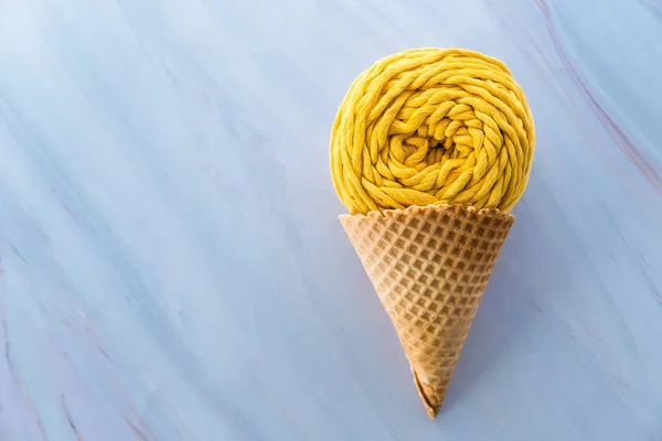 Colocação plana de espinha de fio de macarrão amarelo em cone de waffle de sorvete em um fundo de mármore — Fotografia de Stock