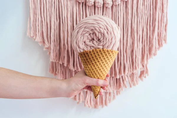 Espinha de fio macrame rosa em cone de sorvete na mão da mulher. — Fotografia de Stock