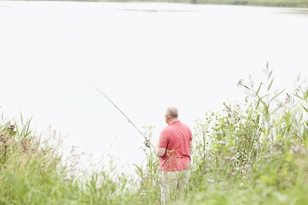 Maturo pescatore cattura di pesce sul lago — Foto Stock