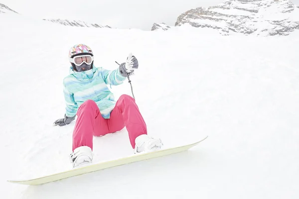 Jonge zittende vrouw met snowboard — Stockfoto