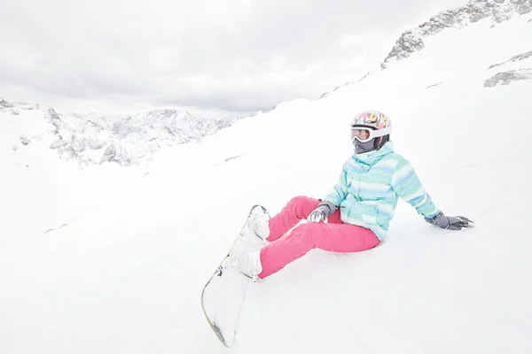 Молодая сидящая женщина с сноубордом — стоковое фото