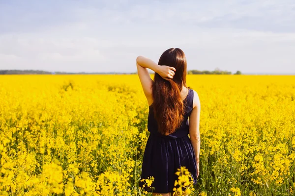 Chica con la mano en el pelo en el prado de colza — Foto de Stock