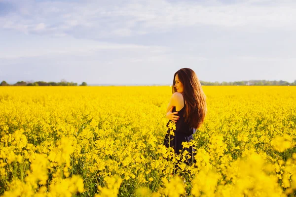 Girl hugs herself on rapeseed meadow — Stock Photo, Image