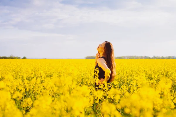 Fille touche son cou sur prairie de colza — Photo