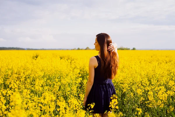 Ragazza con mano nei capelli sul prato di colza — Foto Stock