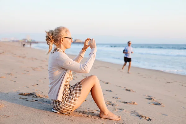 Mujer tomando fotos en la playa — Foto de Stock