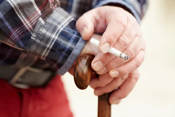 Hands with cigarette on cane — Stock Photo, Image