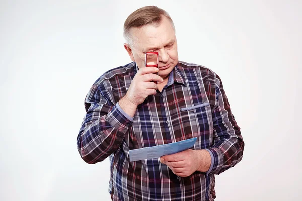 Aged man reading with magnifier — Stock Photo, Image