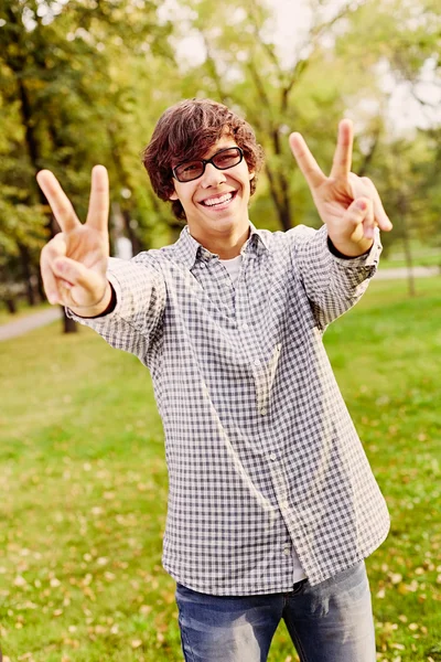 Teenager showing victory sign in park — Stock Photo, Image