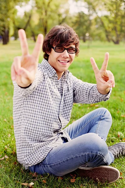 Teenager showing victory sign in park — Stock Photo, Image