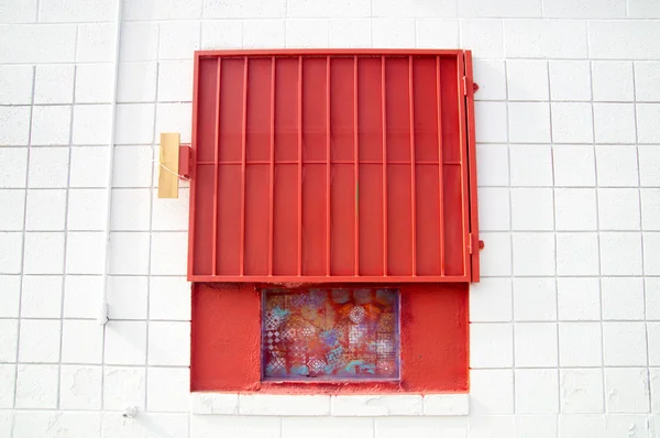 Obturador de malha vermelha na parede branca — Fotografia de Stock