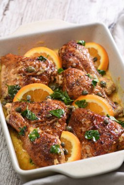 Kremalı soslu fırında tavuk dilimleri, portakallar ve kapari.
