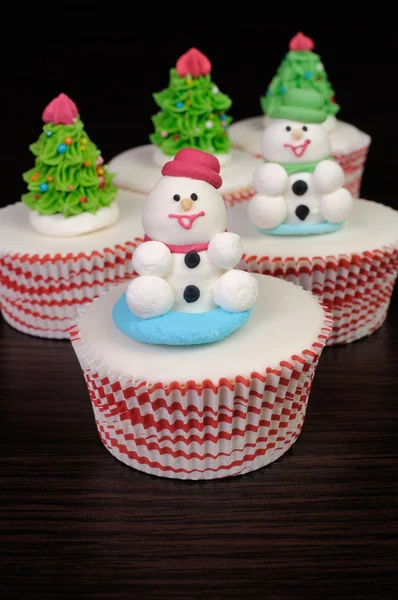 Sugar snowmen figurines on glazed muffins — Stock Photo, Image