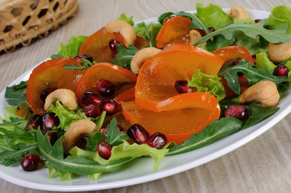 Salad greens with persimmon, pomegranate and cashews — Stock Photo, Image