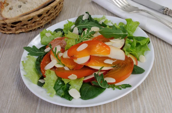 Salad greens with persimmon and almonds — Stock Photo, Image