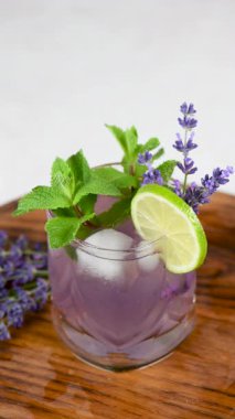 Lavantalı mojito kokteyli, lavanta şurubu, limon suyu, tonikli tekila, lavanta filizi ve nane. Dikey video. Yakın plan. Dairesel hareket