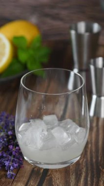 Mavi Göl Kokteyli 'nin limon suyu, votka ve tonik çeşitlerinden yapıyorum. Bir tutam lavanta ve naneli garnitür. Dikey video. Gerçek zamanlı. Yakın plan.