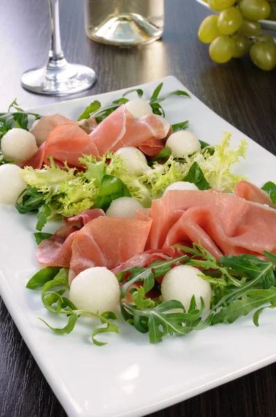 Arugula salad with ham and melon — Stock Photo, Image