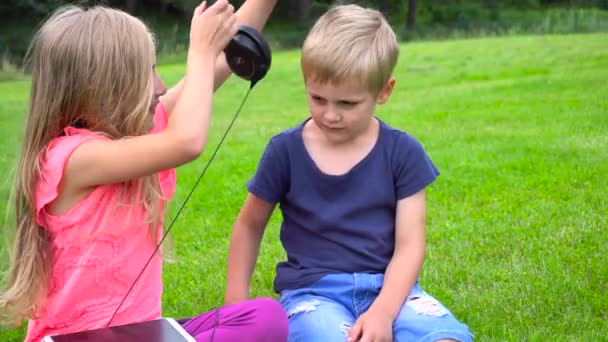 Дети слушают музыку на планшете на открытом воздухе — стоковое видео