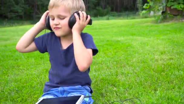 Pojke lyssna musik på tablett utomhus — Stockvideo