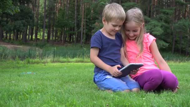 Deux enfants jouant avec la tablette à l'extérieur — Video