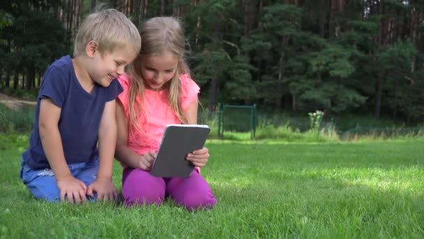 Twee kinderen spelen met tablet buitenshuis — Stockvideo