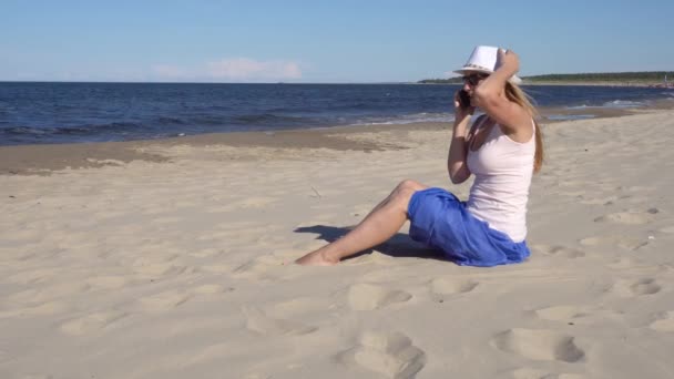 Jonge vrouw praten via de telefoon van de cel op het strand — Stockvideo