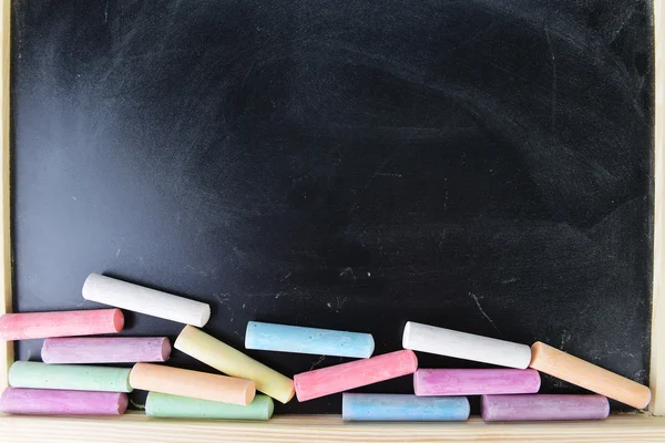 Colorful chalks on blackboard — Stock Photo, Image