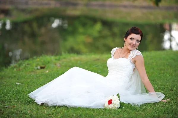 Bride sitting  on grass — Stock Photo, Image