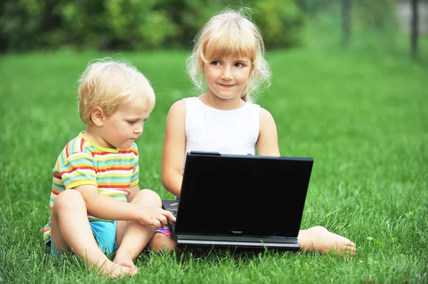 Menina com irmão e laptop — Fotografia de Stock