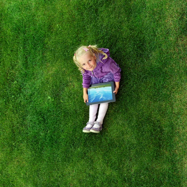 Meisje, zittend op het gras met tablet pc — Stockfoto