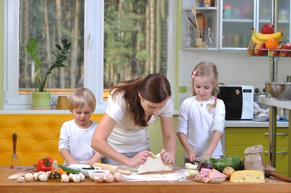 Moeder met kinderen deeg voorbereiden pizza 's — Stockfoto