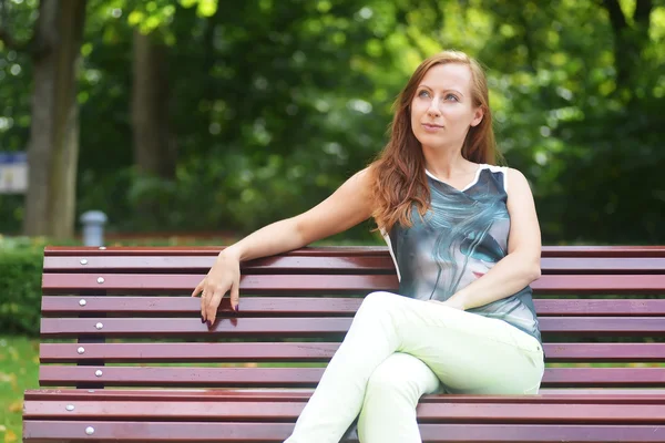 Kvinnan sitter på bänken. — Stockfoto