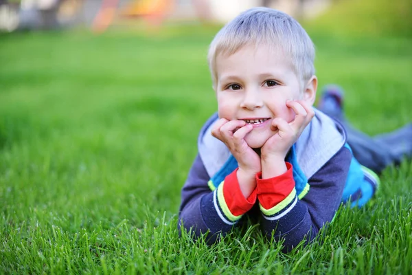 Kleine jongen liggen op gras — Stockfoto