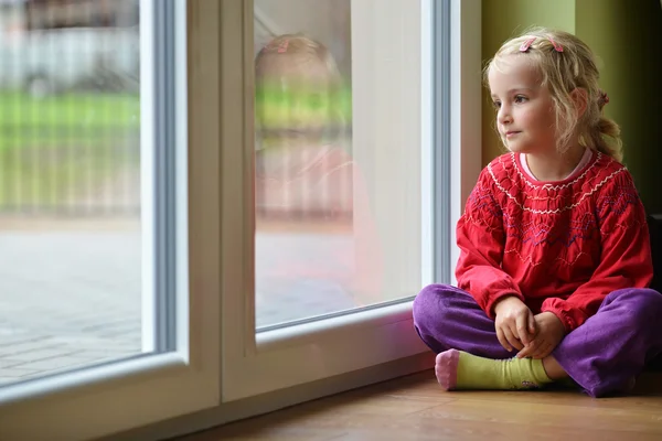 Little girl sits near window — Stock Photo, Image