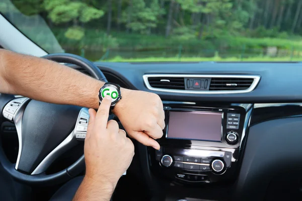 Man points on hand watch while sitting in car — Stock Photo, Image