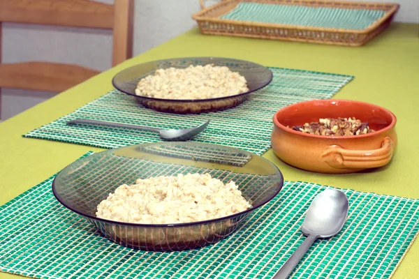 Plates with porridge and brown clay bowl with walnuts to breakfast — Stock Photo, Image