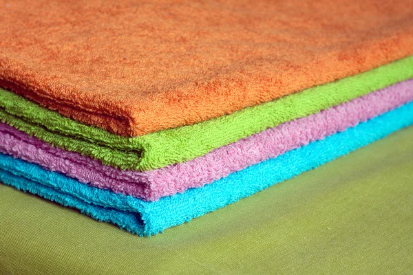 Four bath towels of different colors stacked closeup — Stock Photo, Image