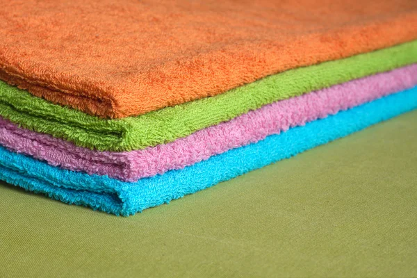 Four bath towels of different colors stacked closeup — Stock Photo, Image