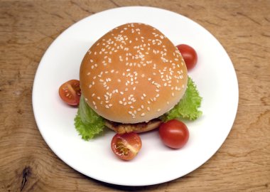 Sığır eti burger salata ve beyaz plaka üzerinde küçük domates