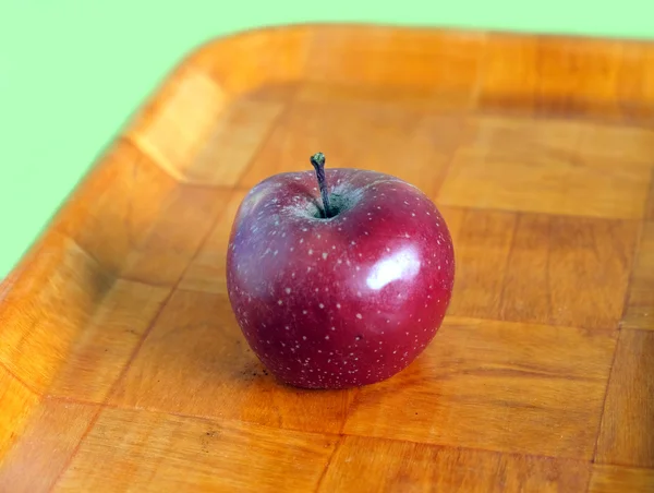 Still life with ripe red apple on brown tray isolated — Stock Photo, Image