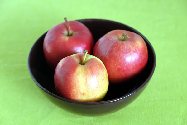 Drei rote Äpfel in lila Schale Nahaufnahme — Stockfoto