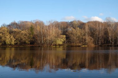 Berrak mavi gökyüzü altında oldukça nehir ve sonbahar renkli ormanlarla sakin bir kırsal alan.